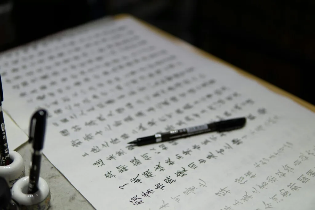 pexels-photo-12356915-12356915 Detailed image of traditional Chinese calligraphy with ink pens and paper.