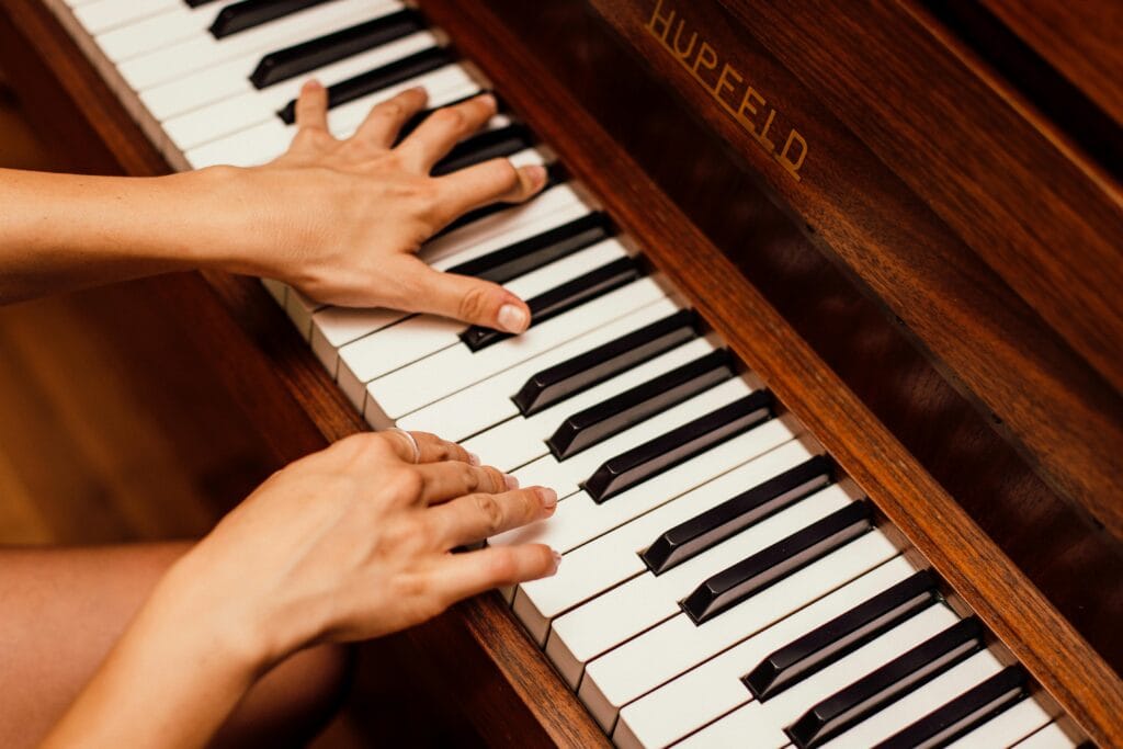 pexels-photo-1246437-1246437 Musician's hands playing wooden piano keys in a high contrast image, capturing musical expression.