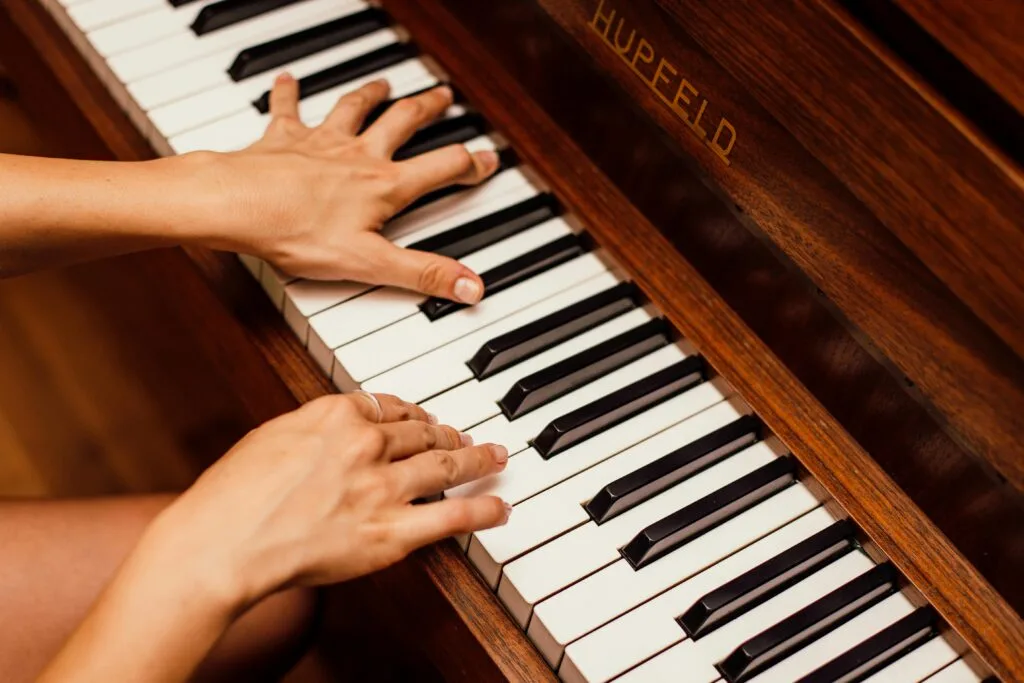 pexels-photo-1246437-1246437 Musician's hands playing wooden piano keys in a high contrast image, capturing musical expression.
